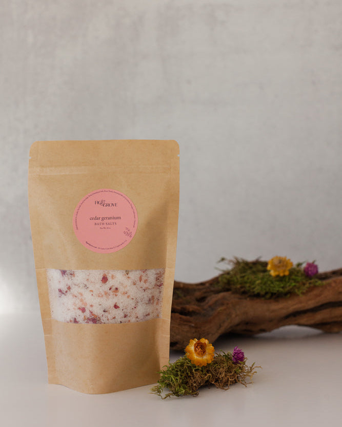 Cedar Geranium essential oil bath salts in a Kraft resealable pouch with a pink label on a neutral background - Fig & Grove