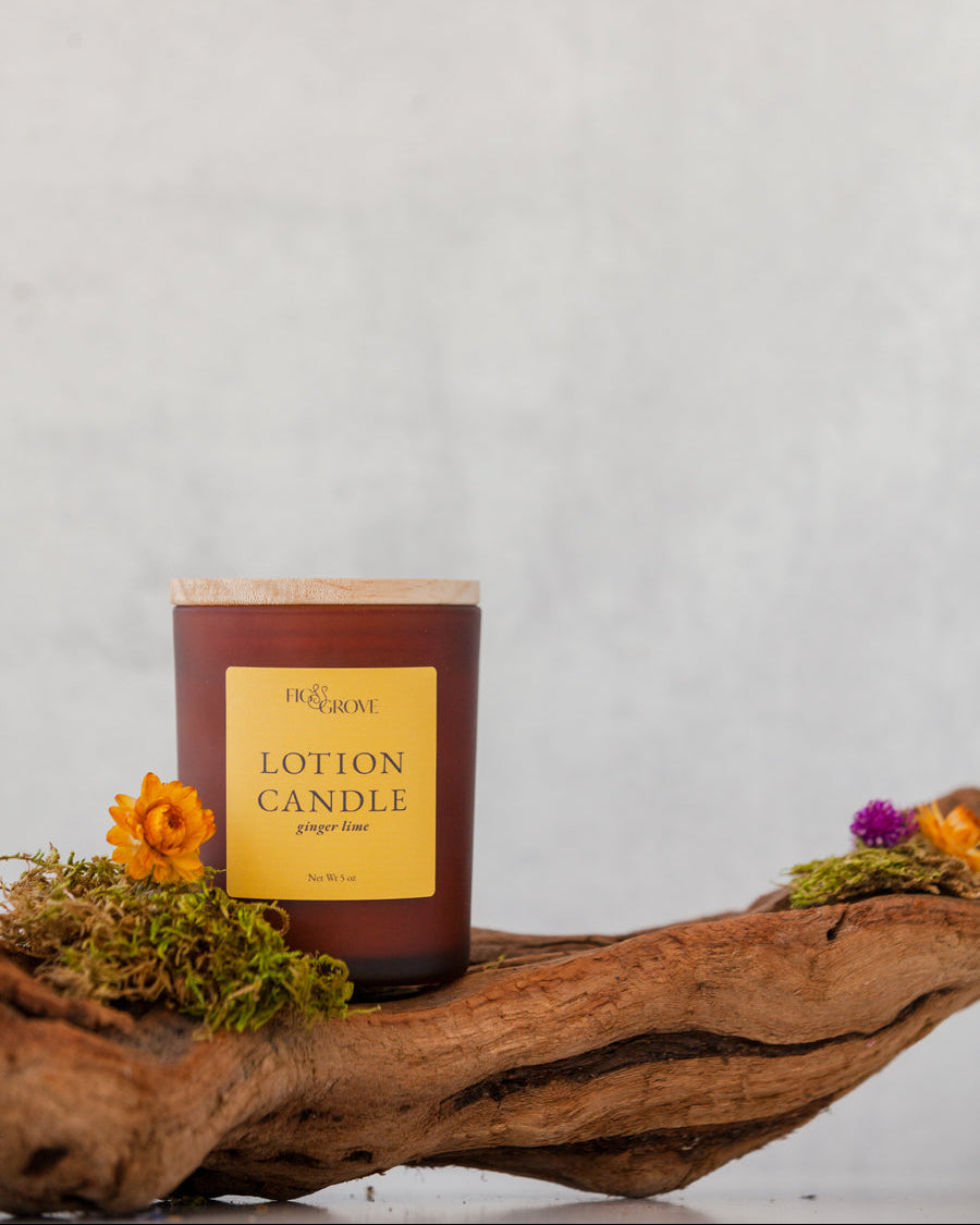 Lotion candle with a yellow label on a wooden surface against a light gray background