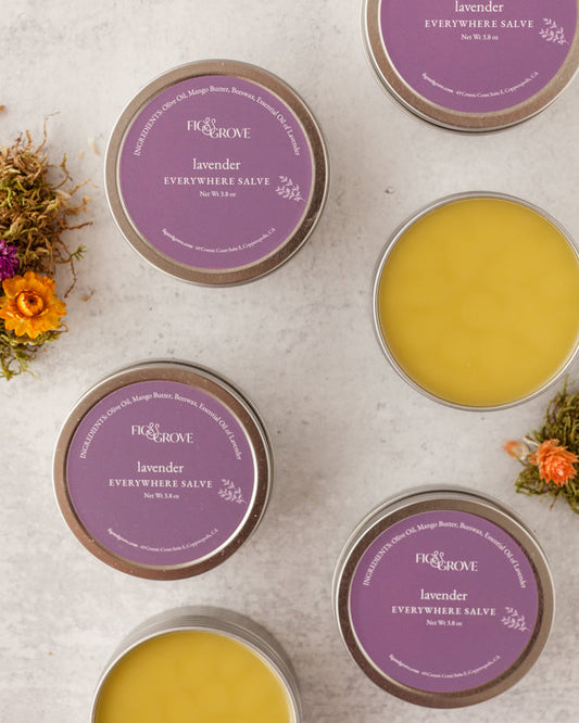 Tins of skin nourishing, soft & buttery Lavender 'Everywhere Salves' with purple labels on a light surface - Fig & Grove