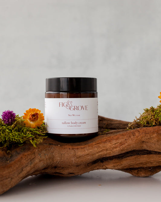 Jar of Fig & Grove regenerative suet tallow body cream on a wooden log with flowers and moss.