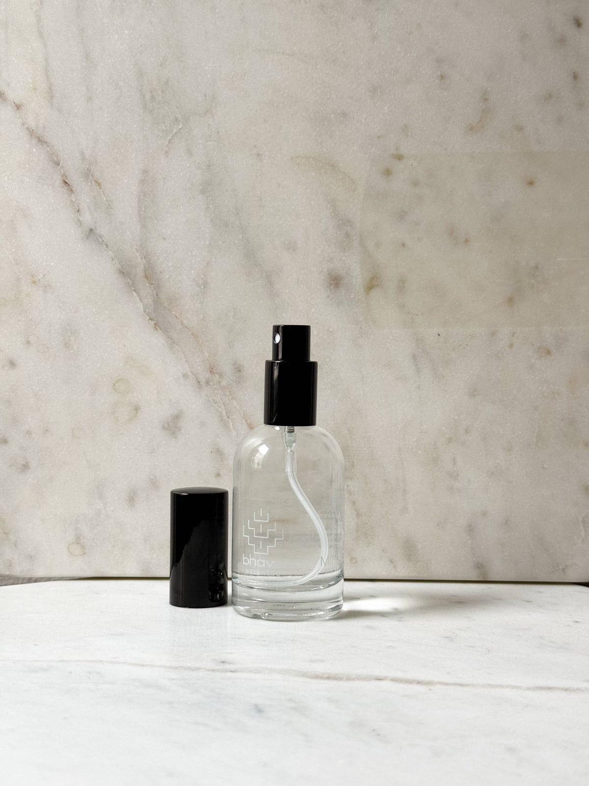 Clear glass bottle with black cap on a marble surface