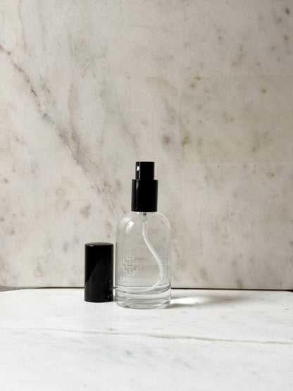 Clear glass bottle with black cap on a marble surface