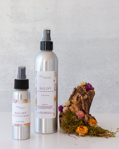 Fig & Grove Bug Off natural bug spray lotion in 80ml and 250ml aluminum bottles displayed with dried wildflowers and driftwood — DEET-free essential oil bug spray made with lavender, citronella, and peppermint
